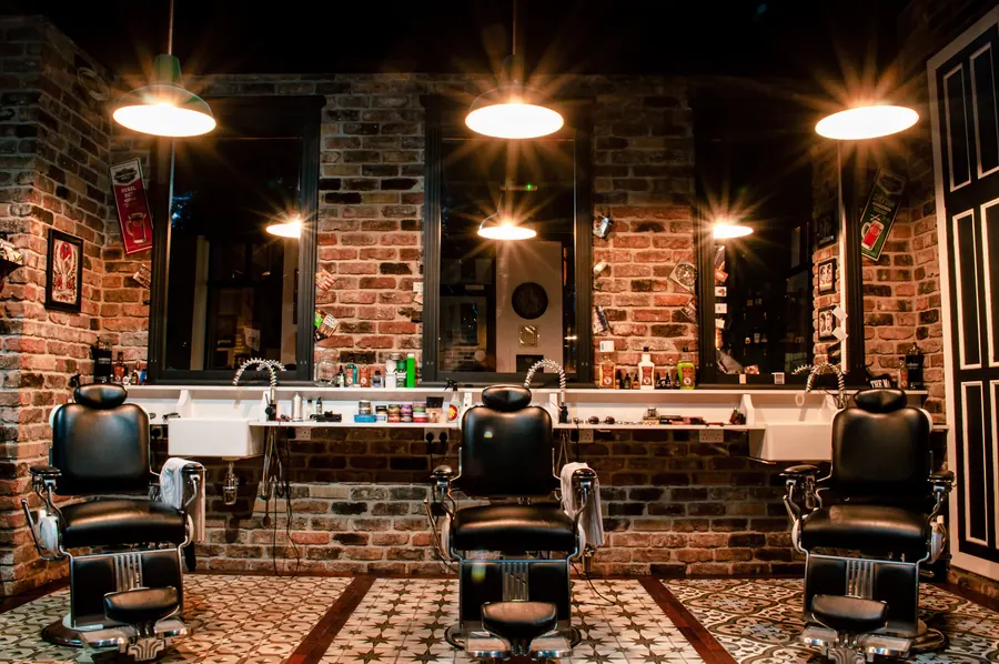 Interior da barbearia com cadeira de couro e parede de tijolos